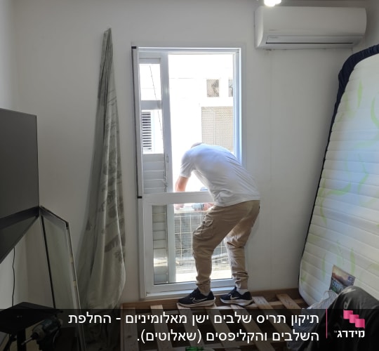 אדם עובד על חלון בחדר עם מיטה